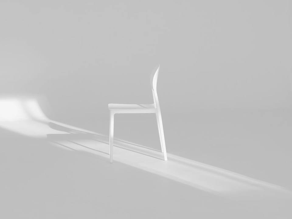 Silla blanca sobre fondo blanco con una franja de luz en el suelo