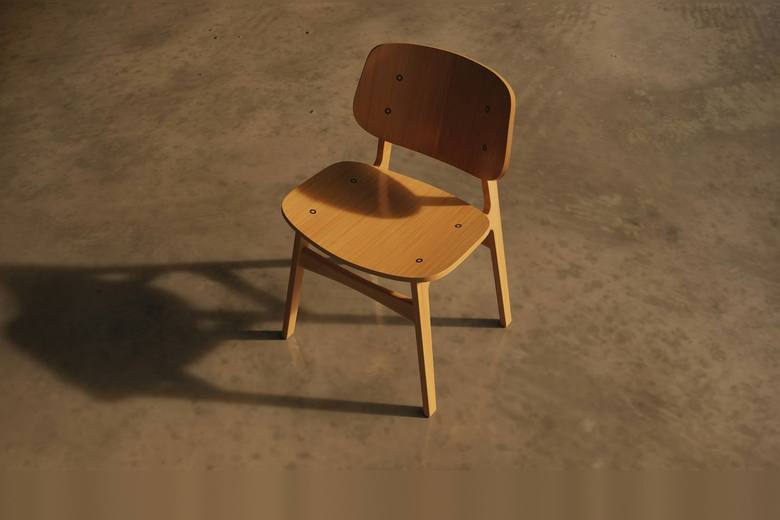 Silla de madera con su sombra sobre un piso de cemento