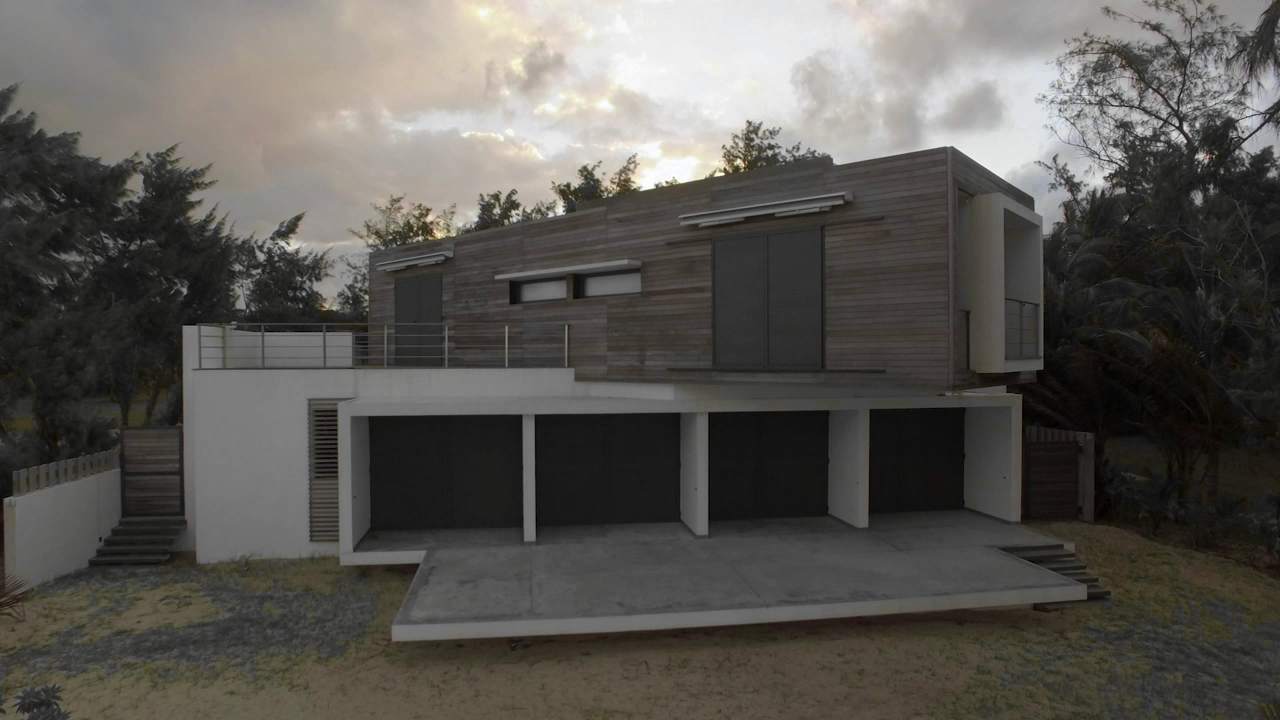 Una casa moderna de madera y hormigón entre árboles, al atardecer