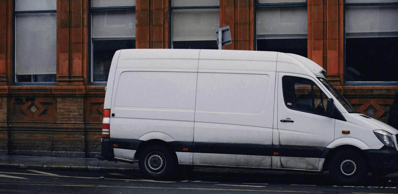 Una furgoneta blanca estacionada junto a un edificio de ladrillo rojo