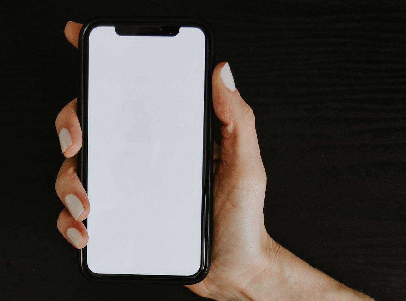 Una mano sostiene un teléfono contra un fondo oscuro, con la pantalla de la cabina de un auto