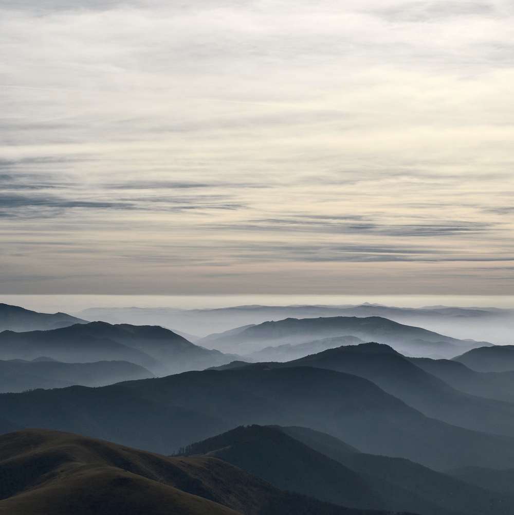 Cresta de montañas entre capas de niebla azul