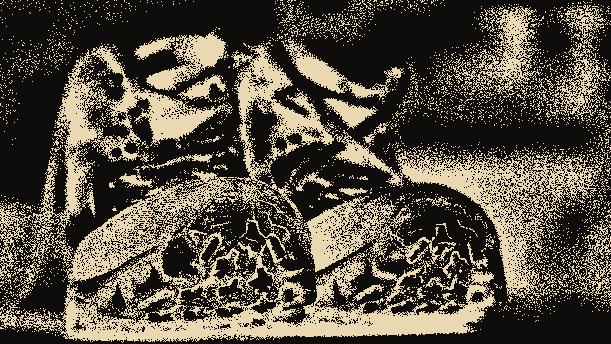 Un par de botas de montaña de frente, con las suelas gastadas, en grano hueso sobre negro