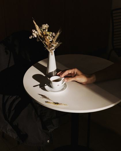Una taza de café sobre una mesa redonda blanca con flores secas