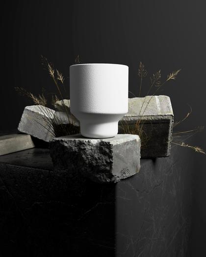 Un vaso blanco sobre piedras, sobre fondo negro