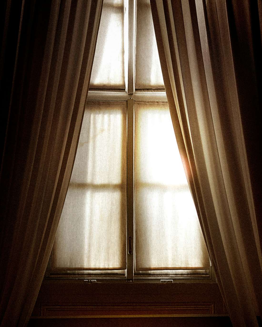 Ventana de pequeños vidrios entre dos cortinas oscuras