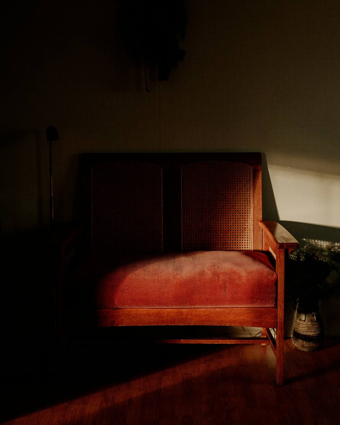 Sillón de madera y tapiz rojizo en una sala casi a oscuras