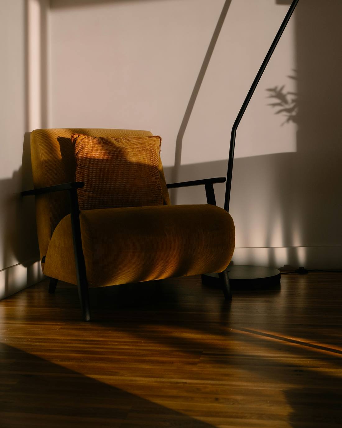 Sillón ocre junto a un muro con sombras largas al atardecer