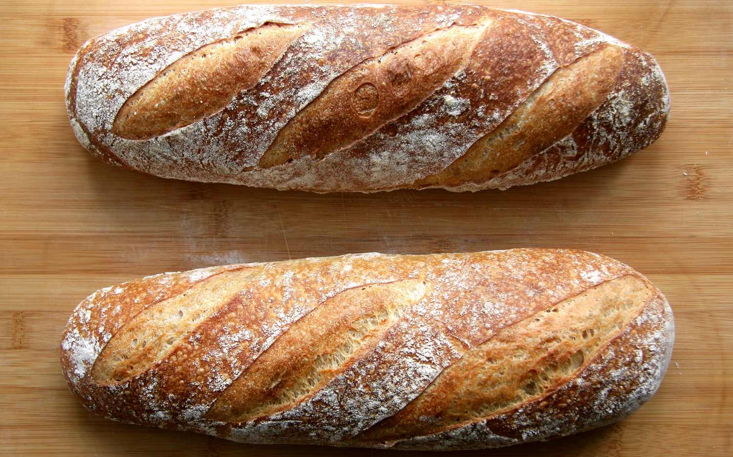 Dos baguettes recién horneadas sobre una tabla de madera