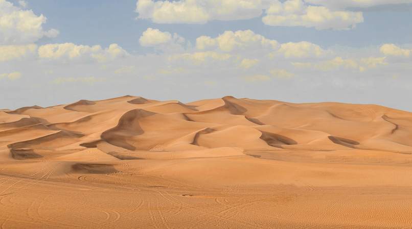 Dunas anchas bajo un cielo con nubes ligeras