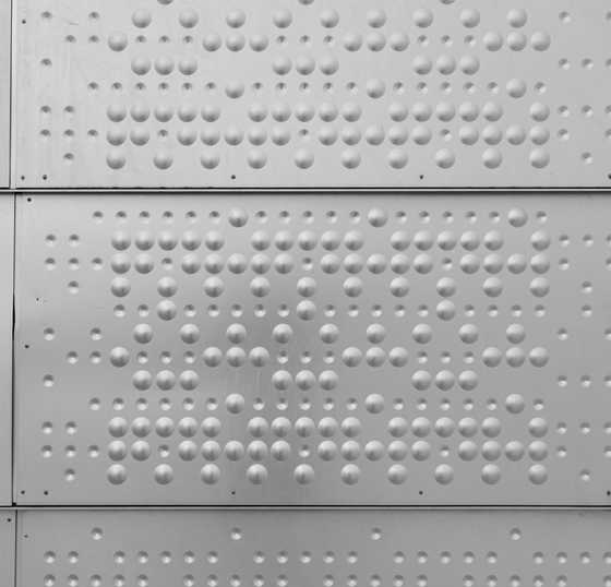 Puntos de braille en relieve sobre una pared blanca