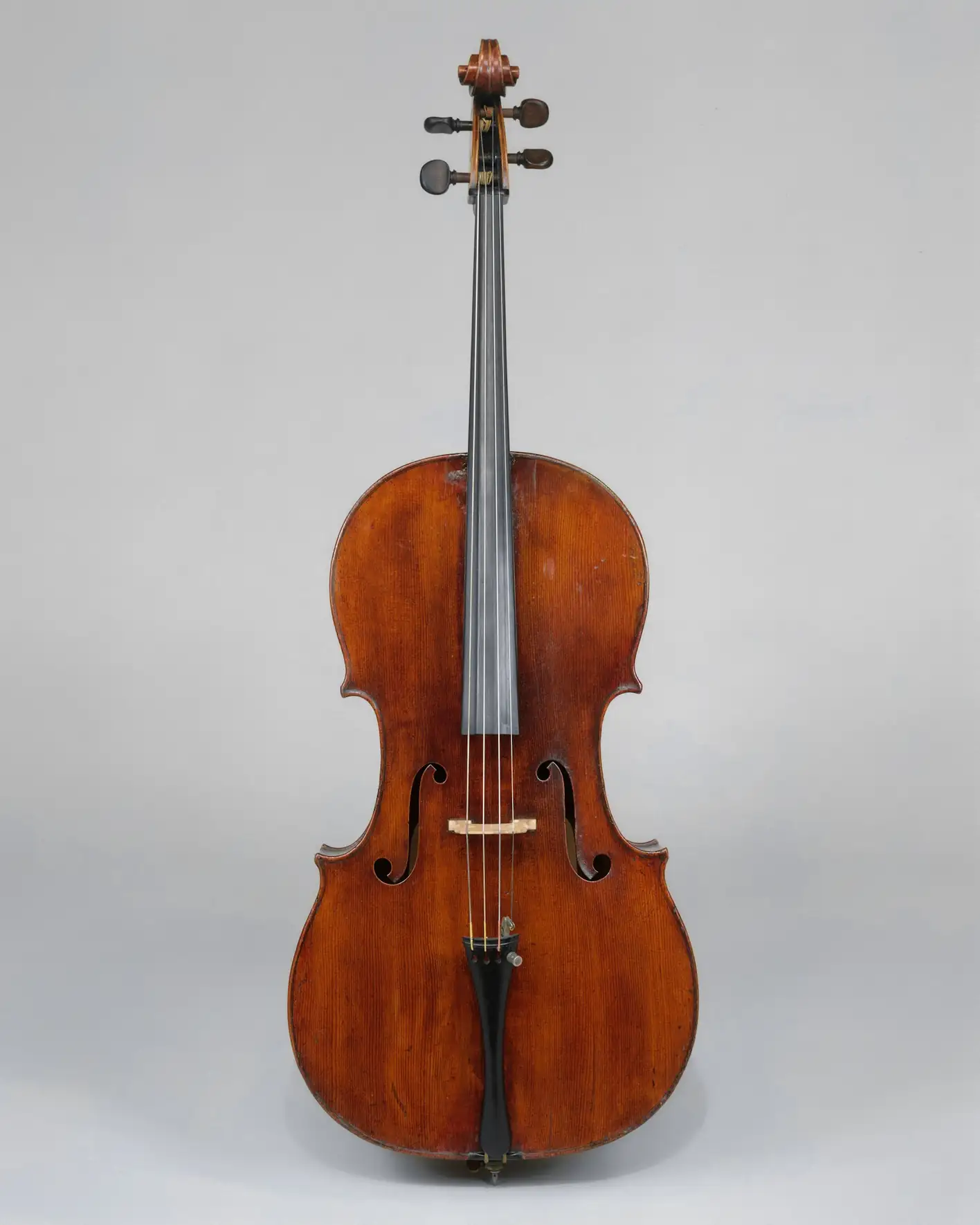 Violonchelo visto de frente sobre un fondo gris claro