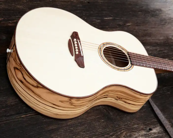 Guitarra de tapa clara sobre una mesa de madera oscura