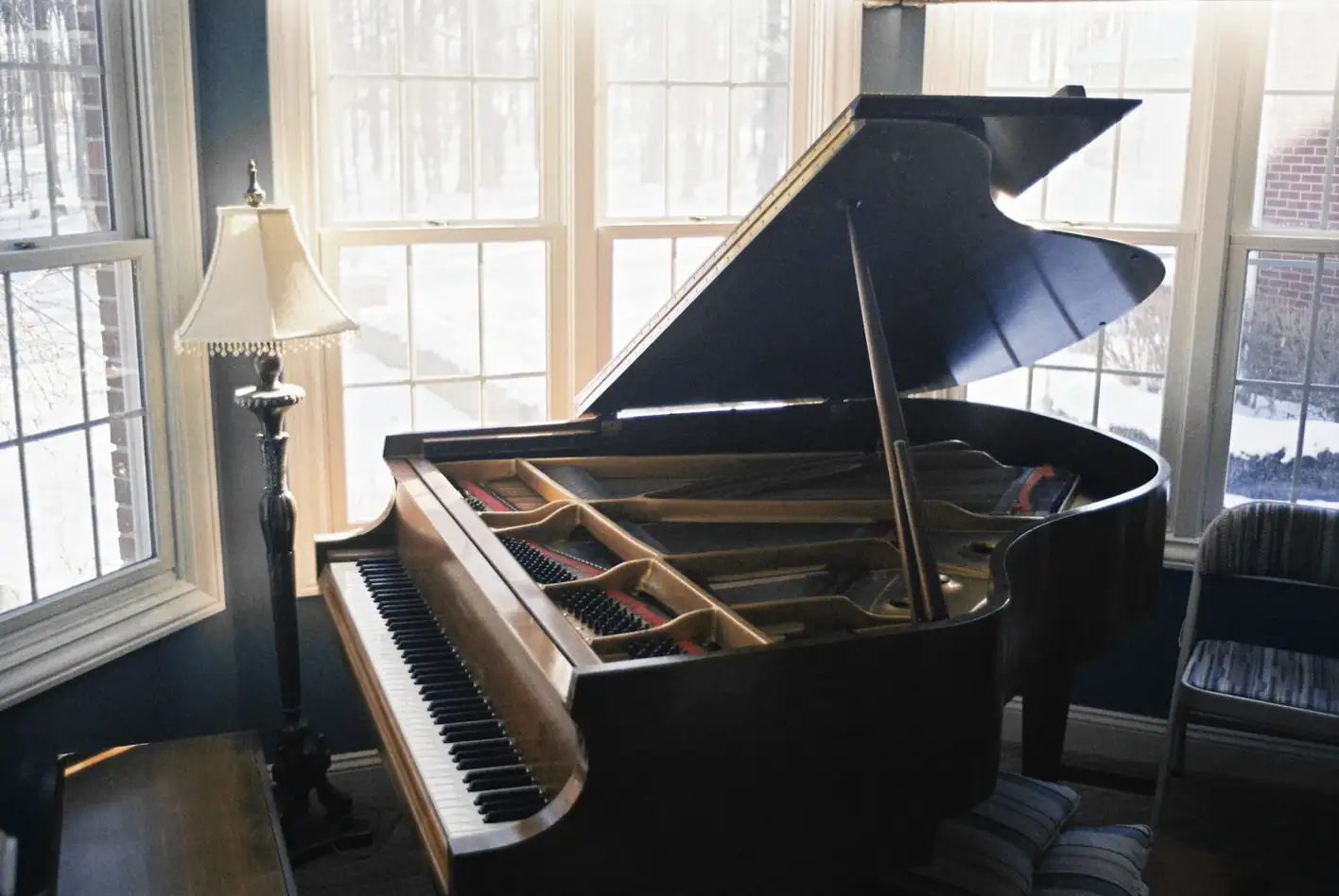 Piano de cola junto a una ventana, con una lámpara al lado