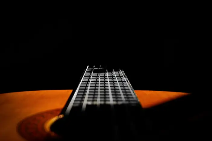 Mástil de una guitarra sobre un fondo negro
