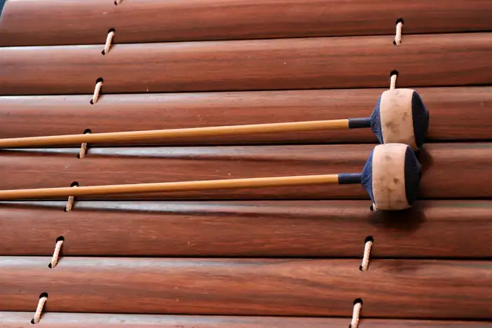 Barras de marimba de madera rojiza con dos mazas