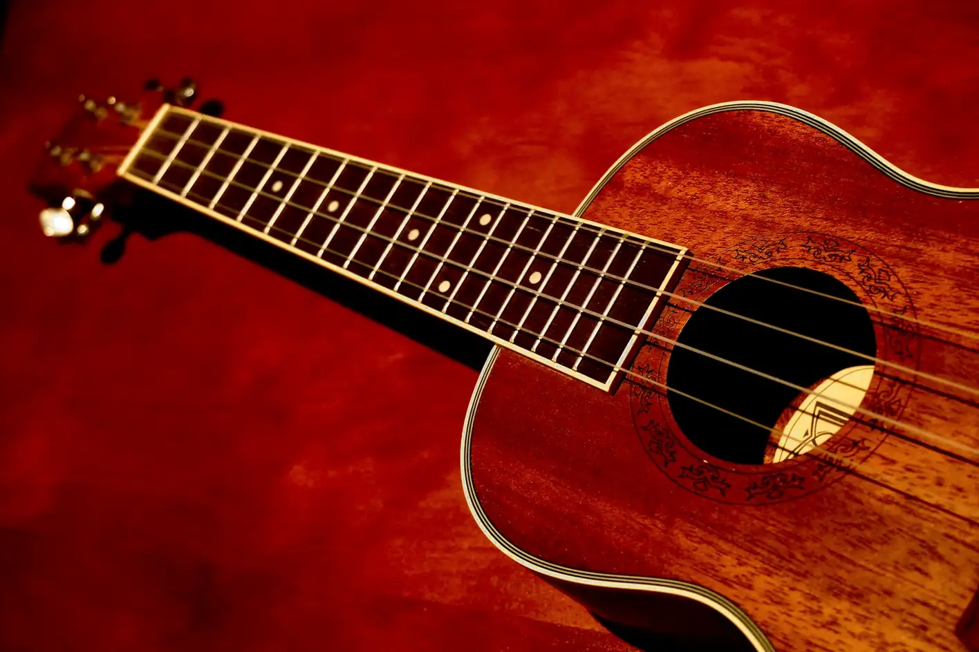 Ukelele de madera sobre un fondo rojo
